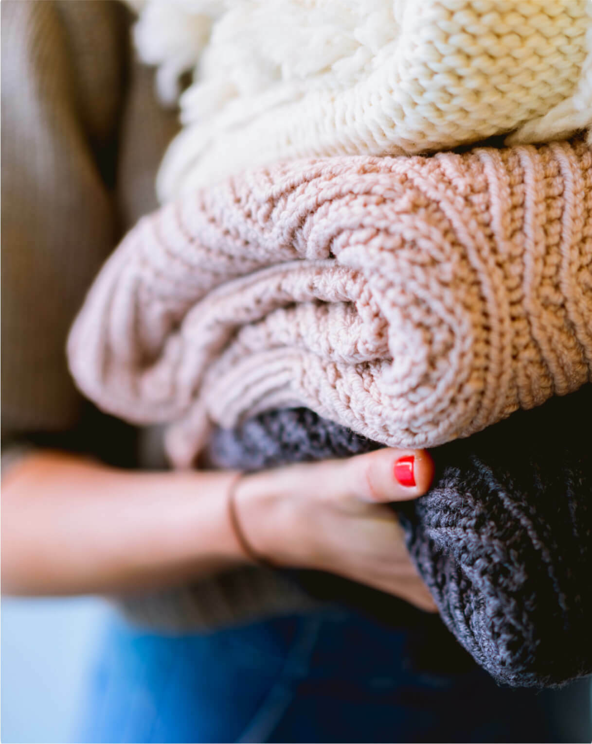 Person holding a pile of folded sweaters